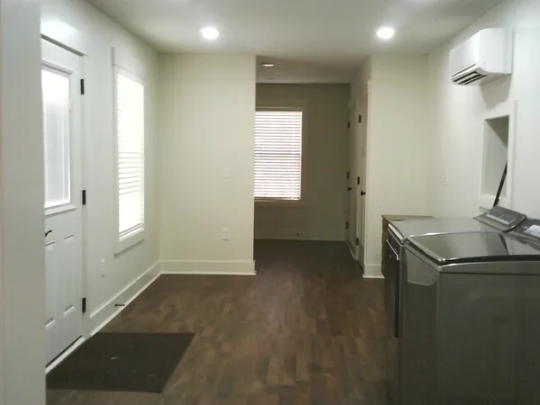 an empty room with wooden floor fireplace and windows