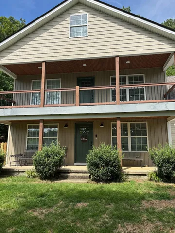 a view of house with a yard potted plants and a table