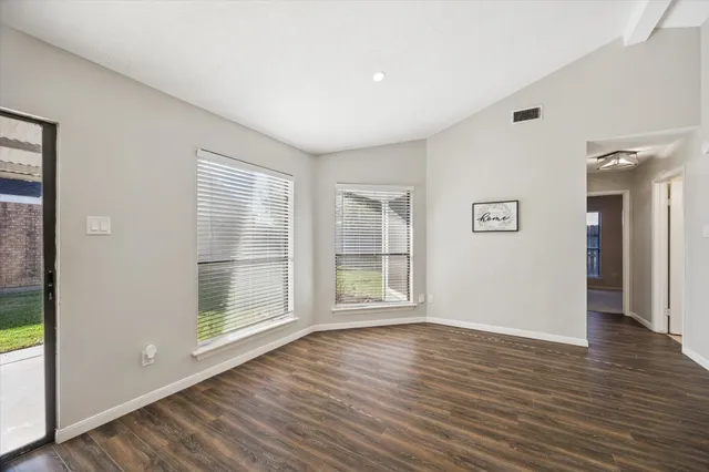 an empty room with wooden floor chandelier fan and windows