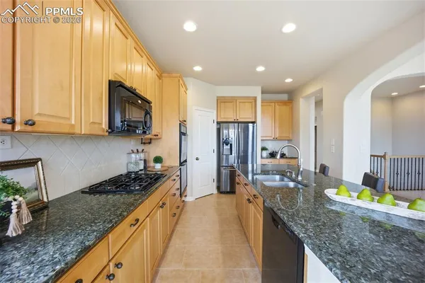 a kitchen with stainless steel appliances granite countertop sink stove refrigerator and cabinets