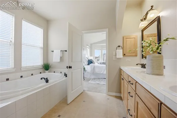 a spacious bathroom with a tub sink and mirror