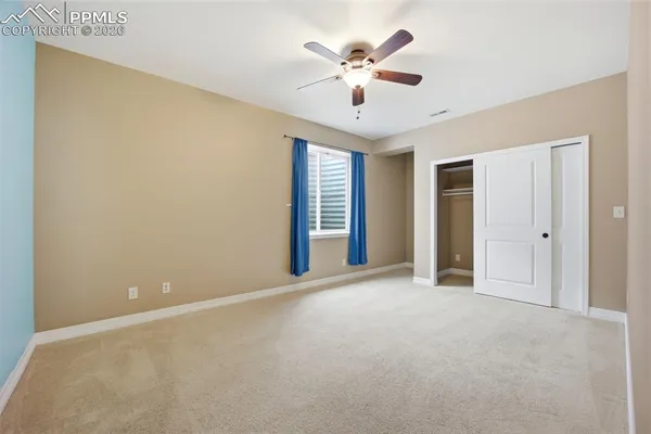 an empty room with chandelier fan and windows