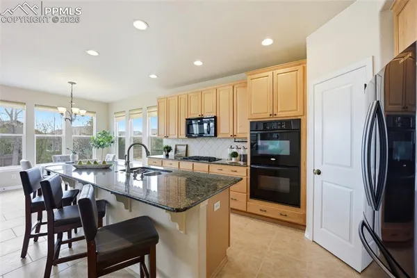 a kitchen with refrigerator a stove and chairs