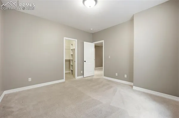 a view of an empty room with chandelier fan