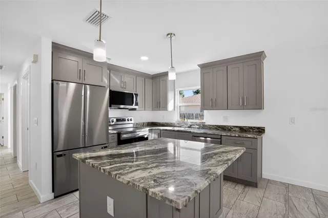 a kitchen with kitchen island a counter space a sink appliances and cabinets