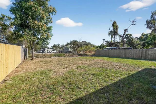 a kitchen with kitchen island granite countertop a stove top oven a sink dishwasher and white cabinets with wooden floor