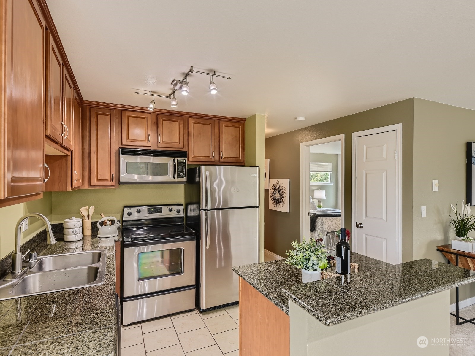 20328 Bothell Everett Highway, Unit B304 Bothell, WA 98012 - Photo 12 of 27 a kitchen with kitchen island granite countertop stainless steel appliances a stove refrigerator sink and cabinets