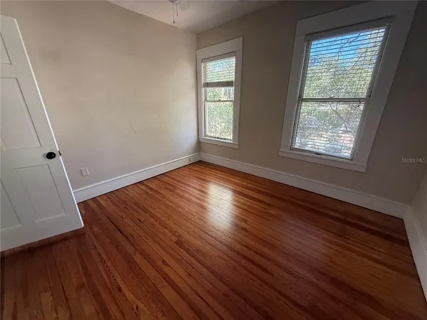 a view of an empty room with wooden floor and a window