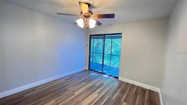 an empty room with wooden floor fan and windows