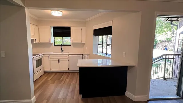 an empty room with wooden floor fireplace and windows