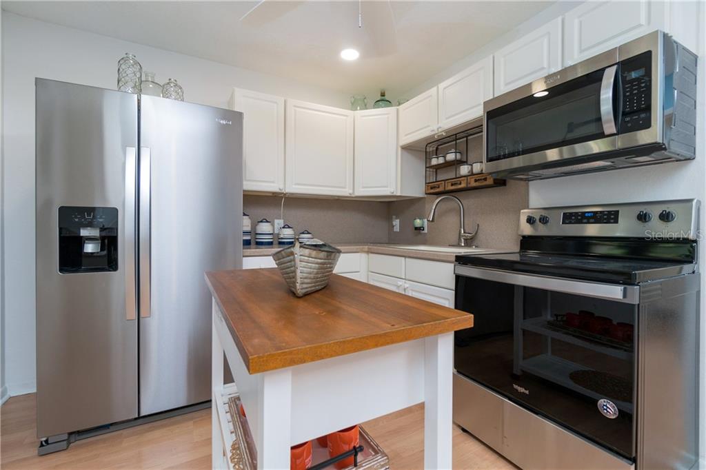 5041 North Beach Road, Unit 3B Englewood, FL 34223 - Photo 3 of 55 a kitchen with stainless steel appliances granite countertop a refrigerator stove top oven and sink