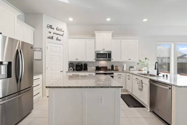 a kitchen with stainless steel appliances granite countertop a refrigerator sink stove microwave and cabinets
