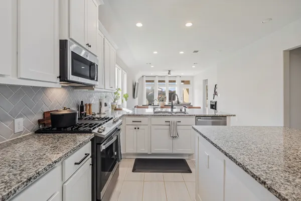 a kitchen with stainless steel appliances granite countertop a sink stove and cabinets