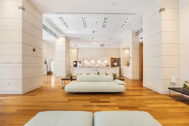 a kitchen with stainless steel appliances kitchen island granite countertop a refrigerator a sink a stove and white cabinets with wooden floor