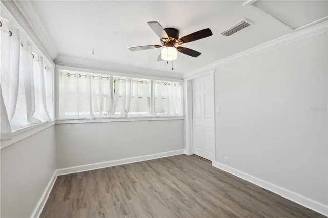 an empty room with wooden floor fan and windows