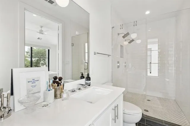 a bathroom with a sink a toilet and shower a mirror