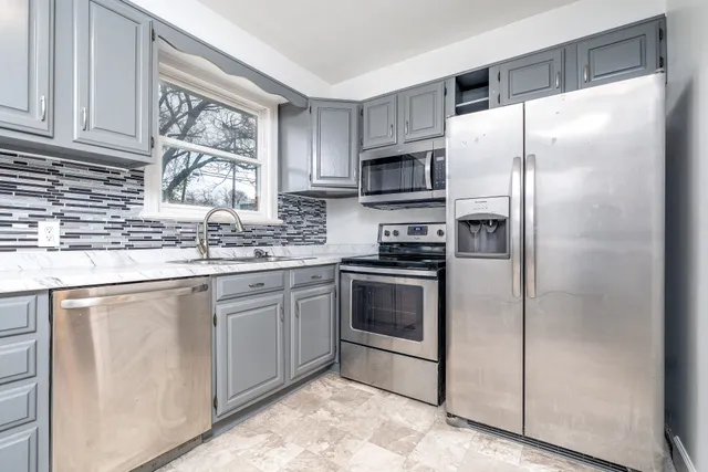 a kitchen with stainless steel appliances granite countertop a refrigerator sink and microwave
