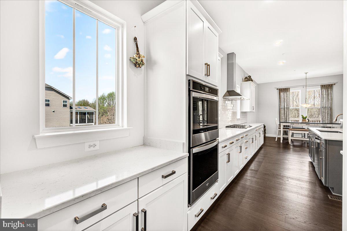 3633 Moline Court Monrovia, MD 21770 - Photo 17 of 82 a kitchen with stainless steel appliances a stove a sink and white cabinets with wooden floor