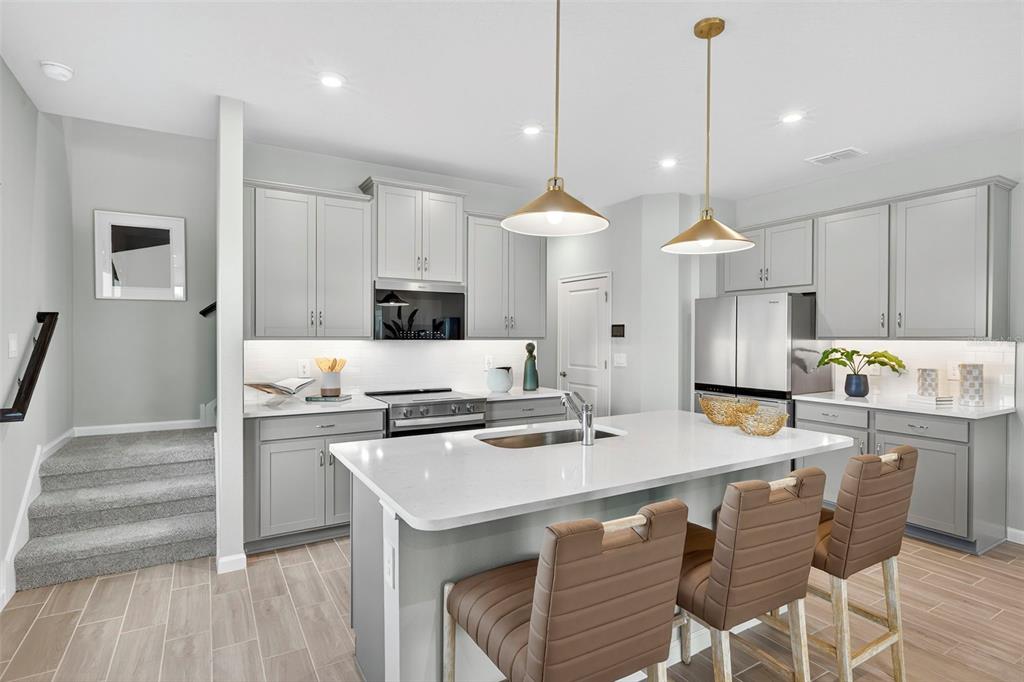 8830 Ginko Run Parrish, FL 34219 - Photo 7 of 29 a kitchen with stainless steel appliances kitchen island granite countertop a stove a refrigerator a sink and white cabinets with wooden floor