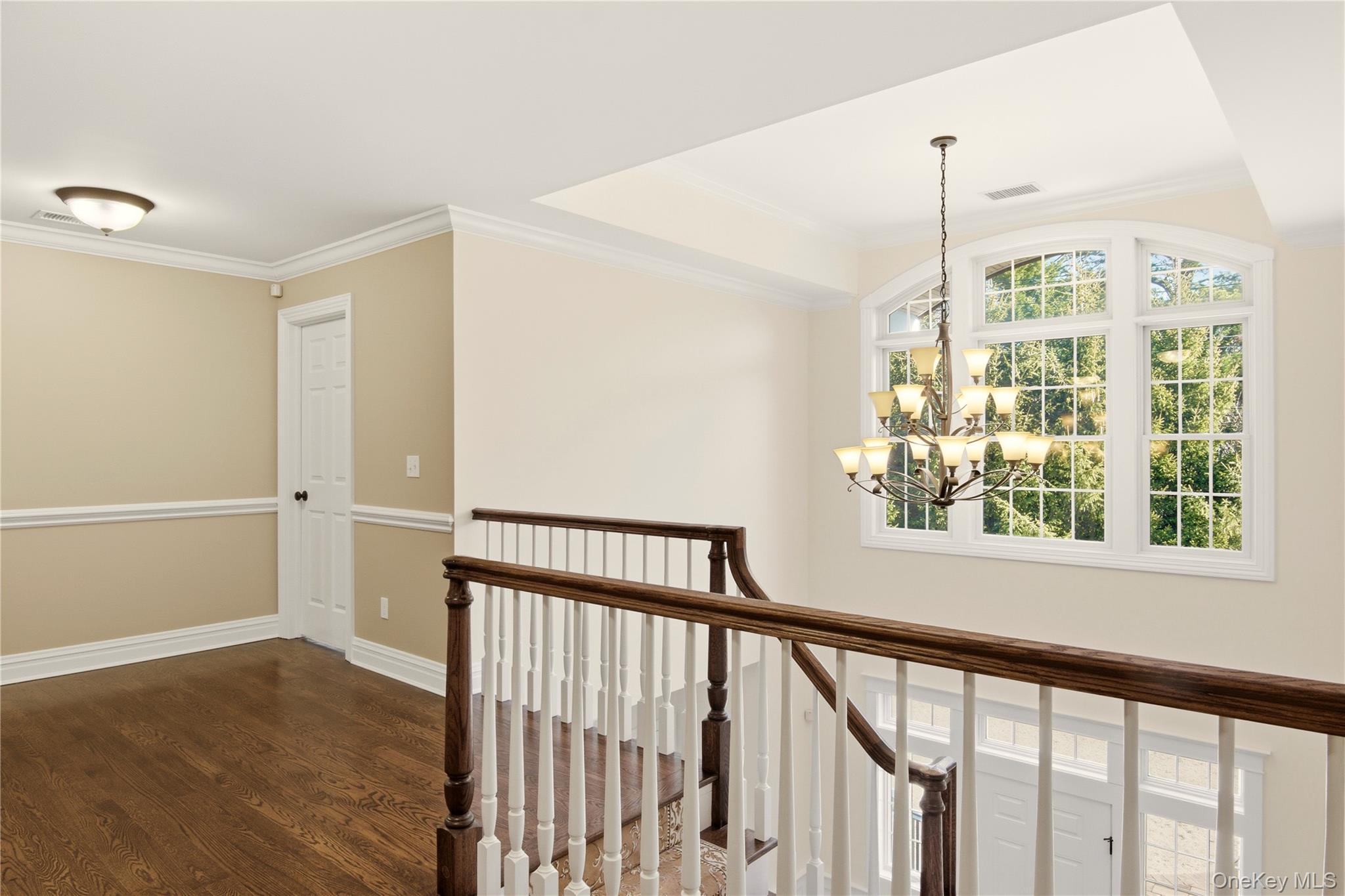 69 Old Depot Road Quogue, NY 11959 - Photo 16 of 40 Hallway featuring ornamental molding, dark wood-style flooring, a chandelier, and an upstairs landing