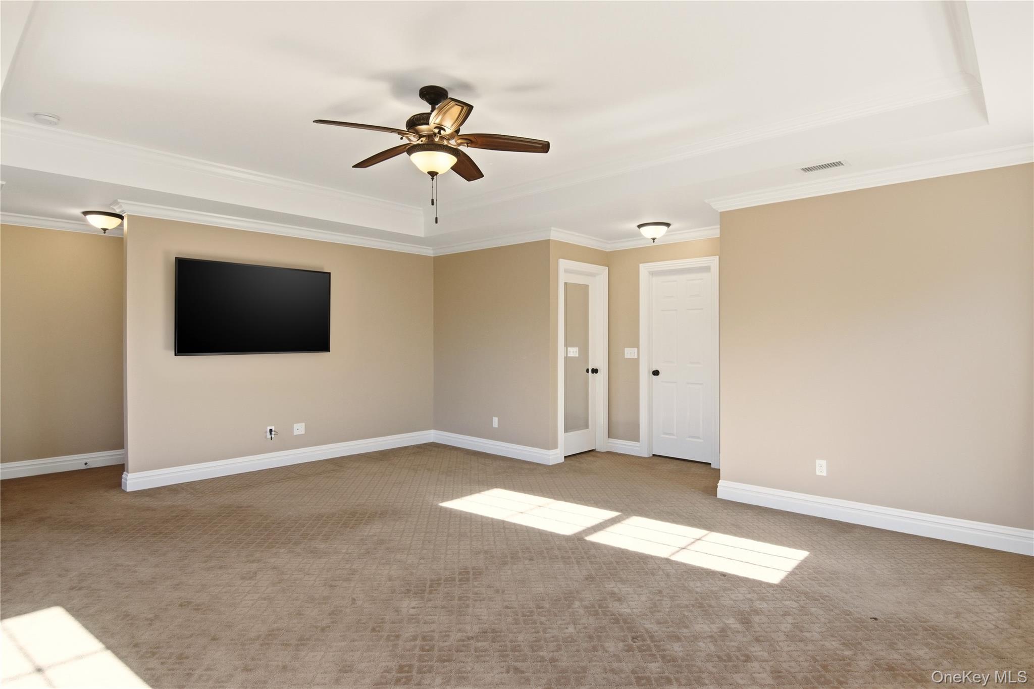 69 Old Depot Road Quogue, NY 11959 - Photo 30 of 40 Empty room featuring a ceiling fan, light carpet, a tray ceiling, and ornamental molding