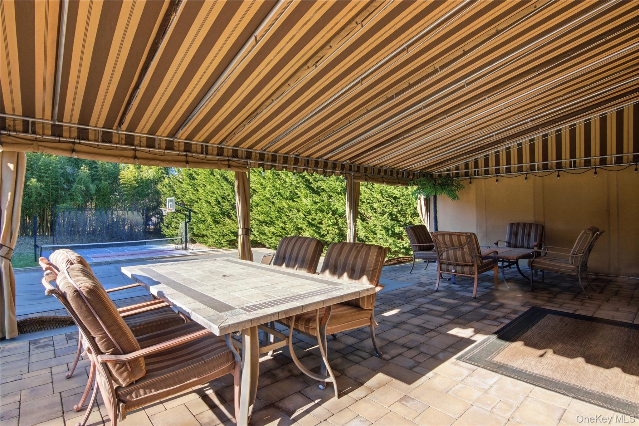 69 Old Depot Road Quogue, NY 11959 - Photo 41 of 44 a view of a patio with table and chairs and couches with wooden floor and fence with barbeque grill