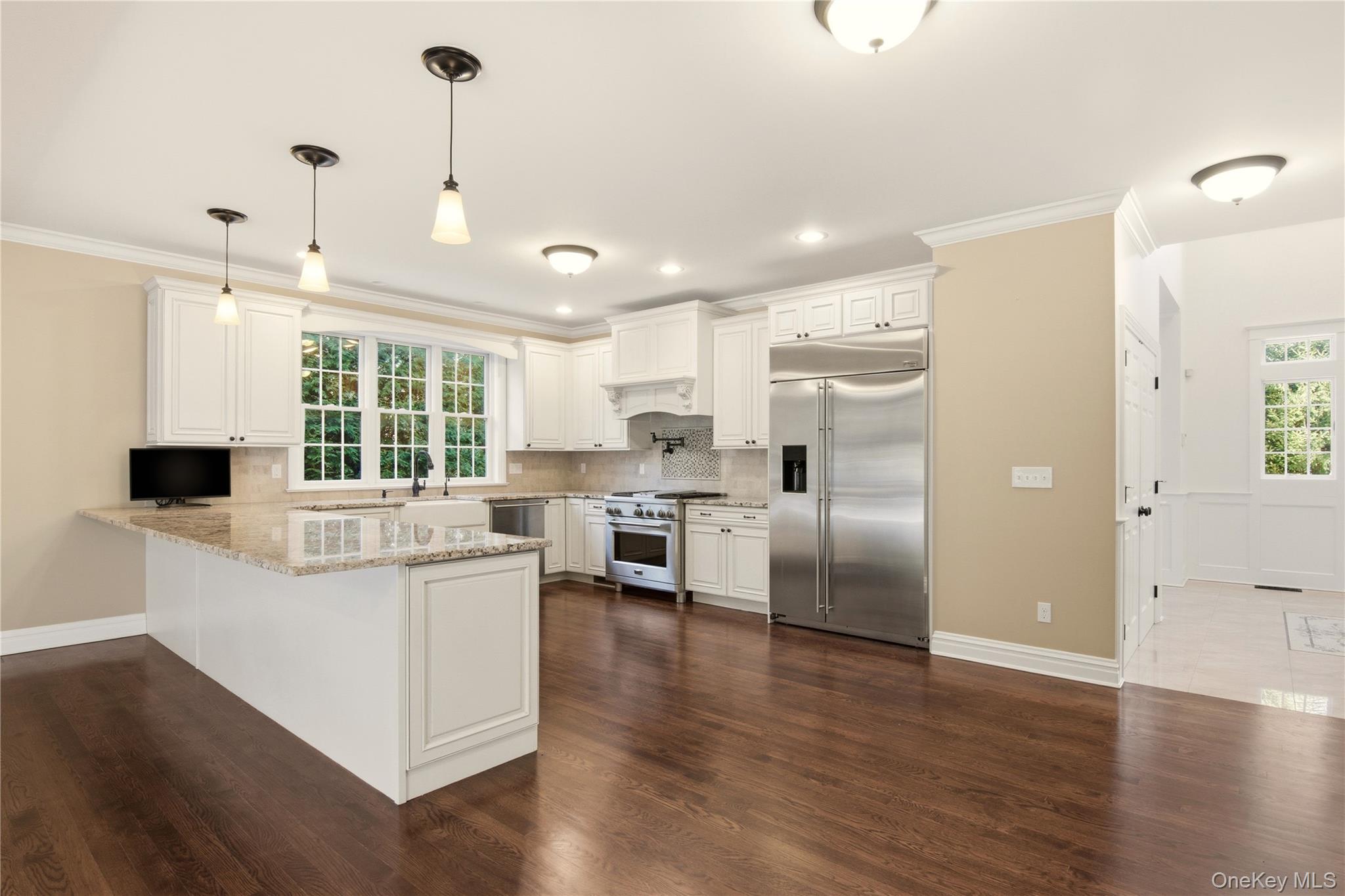 69 Old Depot Road Quogue, NY 11959 - Photo 9 of 40 Kitchen featuring ornamental molding, high quality appliances, healthy amount of natural light, hanging light fixtures, and a peninsula