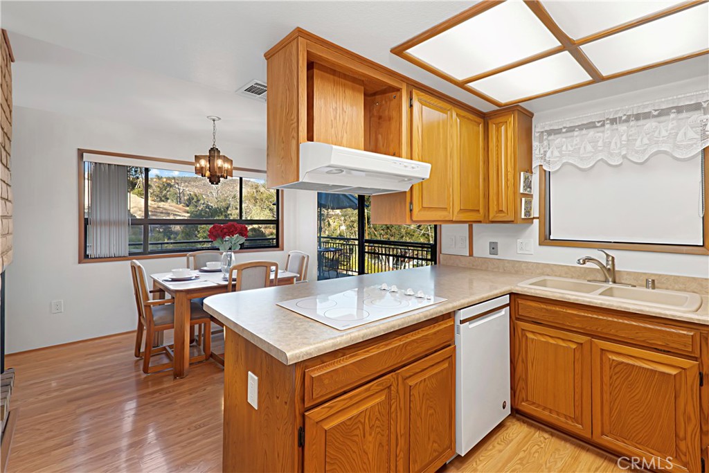 11879 Rocoso Road Lakeside, CA 92040 - Photo 13 of 25 a kitchen with stainless steel appliances granite countertop a sink a stove and wooden floors