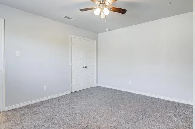 a view of an empty room with a chandelier fan