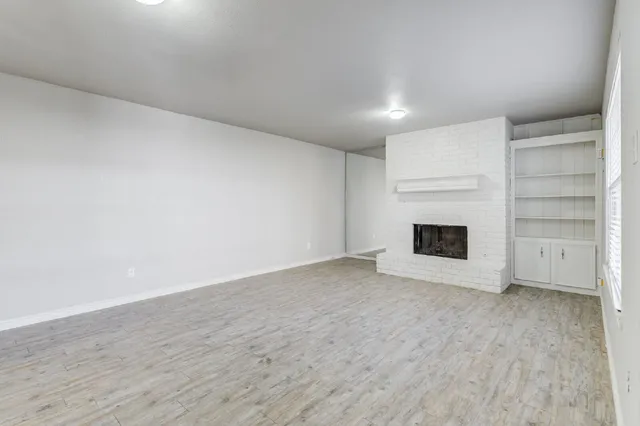 a view of an empty room with a fireplace and a window