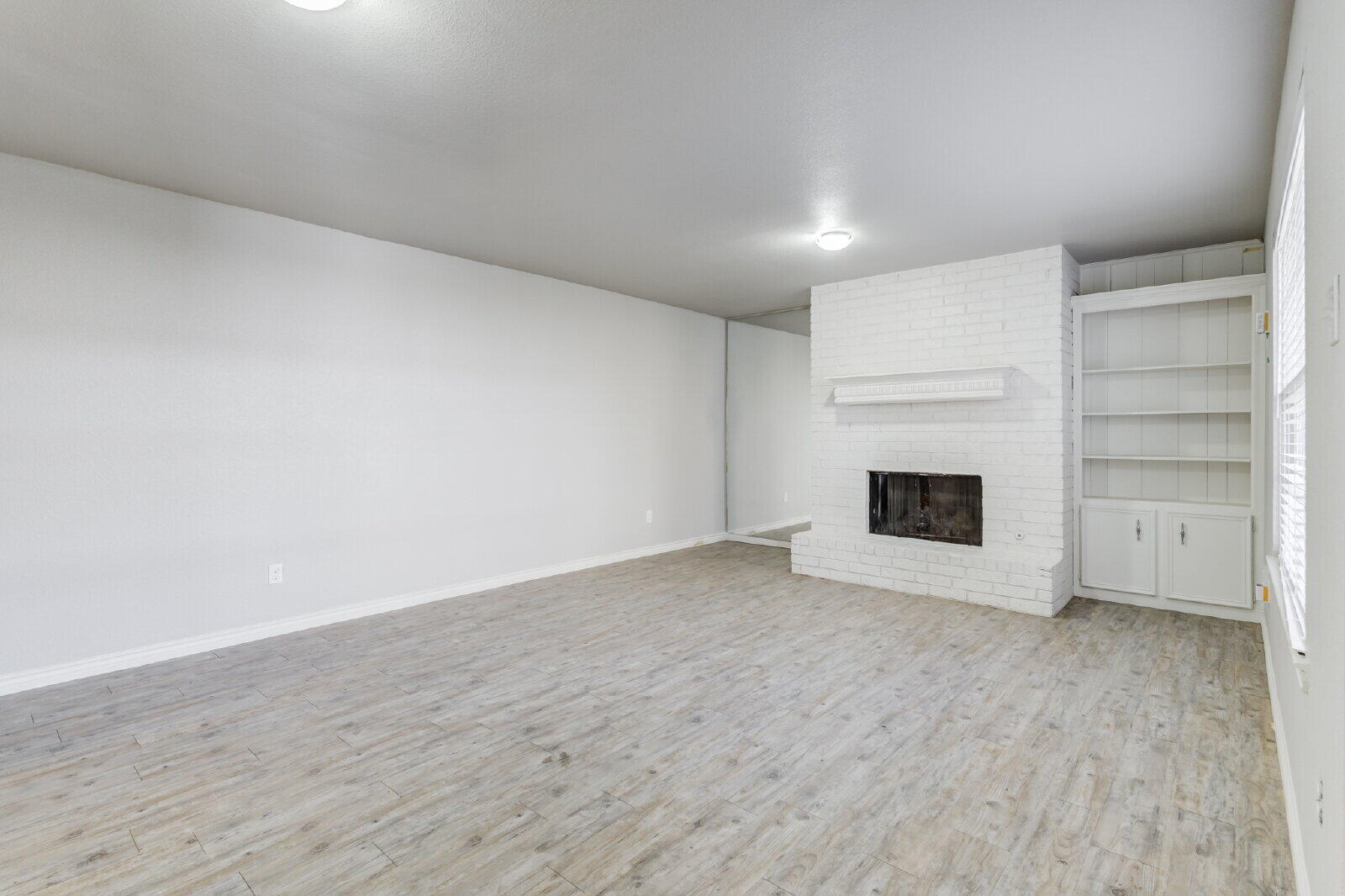4320 52nd Street, Unit B Lubbock, TX 79413 - Photo 3 of 25 a view of an empty room with a fireplace and a window
