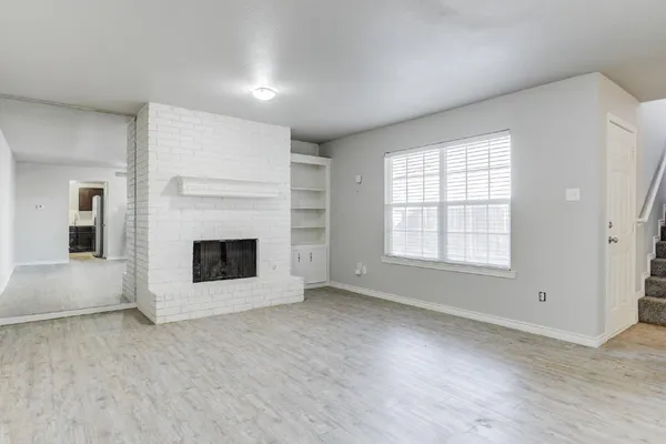 an empty room with windows and fireplace