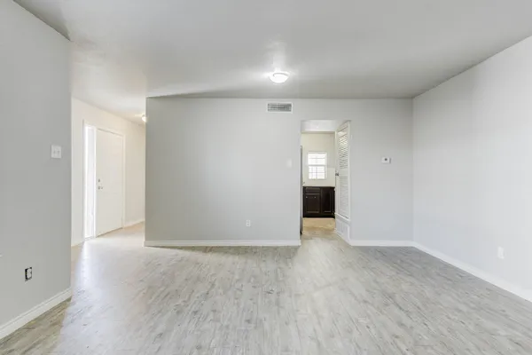 a view of an empty room with wooden floor and cabinets
