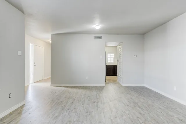 a view of an empty room with wooden floor and cabinets
