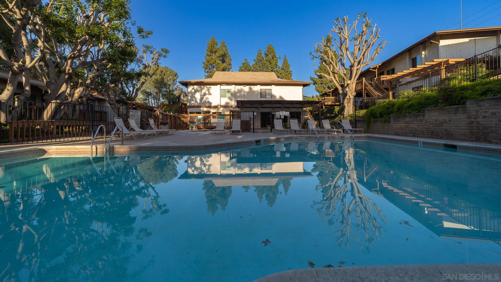 a small pool with tables and chairs next to a yard