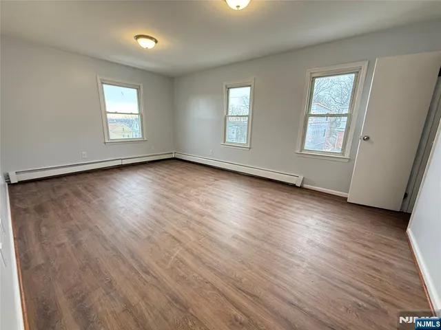 a view of an empty room with wooden floor and window