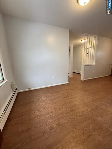 an empty room with stairs and wooden floor