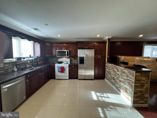 a large kitchen with stainless steel appliances kitchen island granite countertop a sink and cabinets