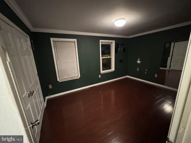 en empty room with wooden floor and windows