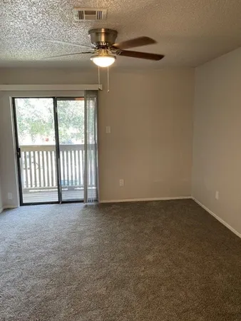 a view of an empty room with chandelier fan