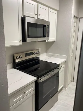 a kitchen with granite countertop white cabinets and black appliances