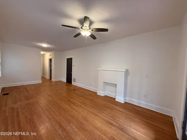 a view of empty room with wooden floor and ceiling fan
