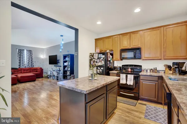 a kitchen with stainless steel appliances granite countertop a stove top oven a sink dishwasher and a refrigerator with wooden floor