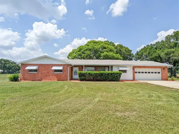 a front view of house with yard and trees in the background