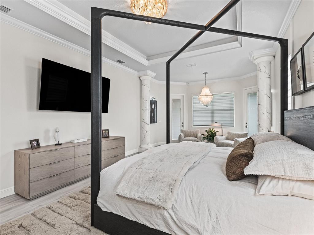 7161 Northeast 22nd Ct Road Ocala, FL 34479 - Photo 49 of 81 a bedroom with a bed a flat screen tv and a chandelier