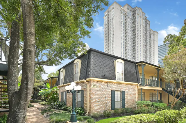 a front view of a residential apartment building with a yard and potted plants
