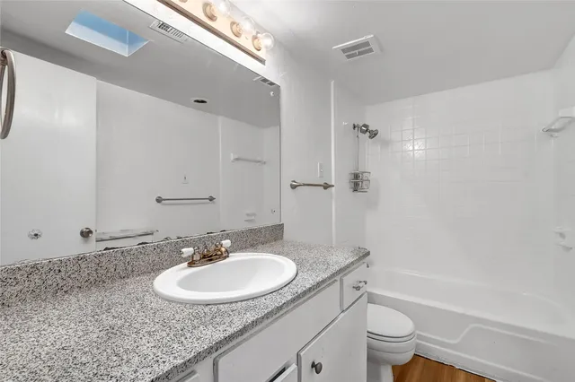 a bathroom with a granite countertop sink toilet and shower