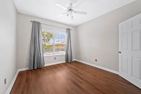 an empty room with wooden floor and windows