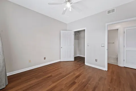 an empty room with wooden floor and ceiling fan