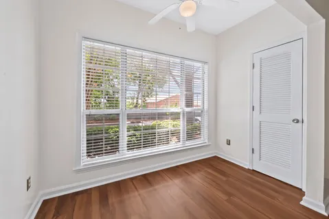 a view of an empty room with wooden floor and a window